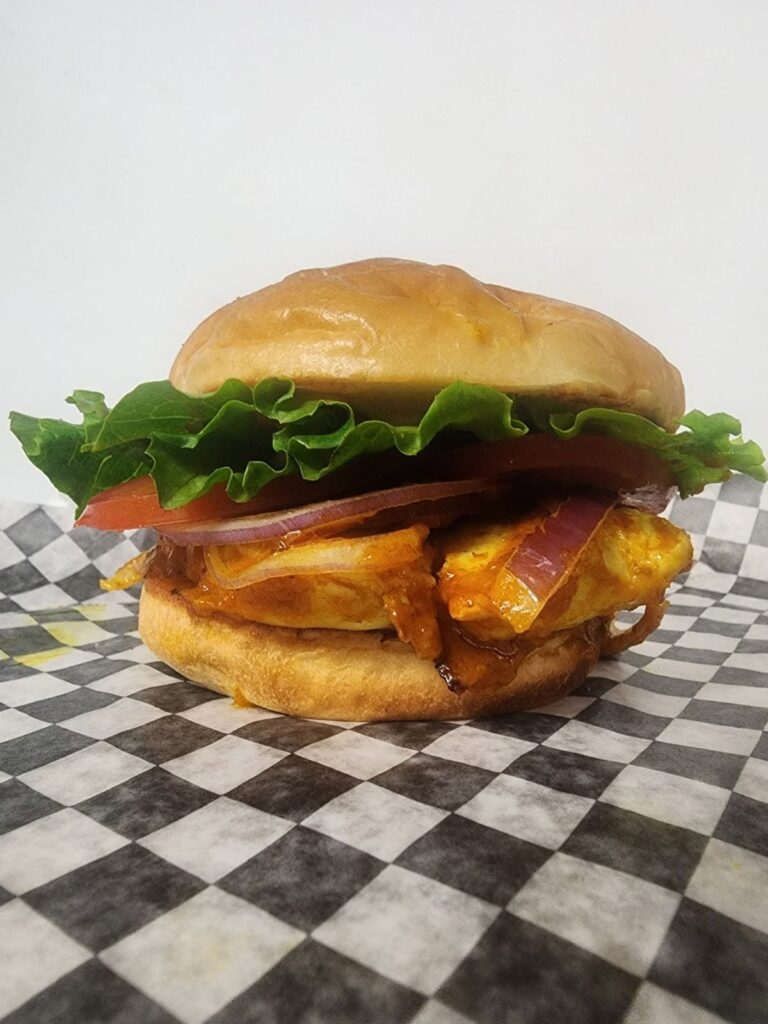 Grilled chicken sandwich with lettuce, tomato, and red onion from Smashed YXY